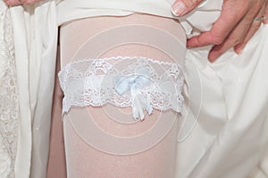 Sexy garter placed on a bride`s leg. Part of a girl`s body.