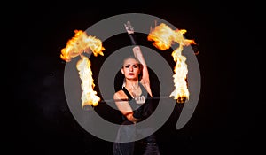 Sexy girl artist twirl burning batons during sparkling fire performance in darkness, lighting