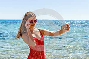 girl on a beach with surprised expression looking at phone and taking selfie