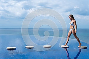 Sexy girl. beautiful woman. model lady bikini underwear sit edge of water swim pool on the roof of luxury resort hotel