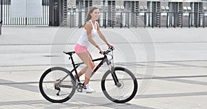 Sexy girl with bicycle. Young slim sexy sporty woman in pink shorts and white snickers long-haired
