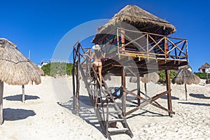 Sexy girl climbing the watchtower of the beach watchmen on the paradisiacal beach of dolphins beach in Cancun, Mexico. photo