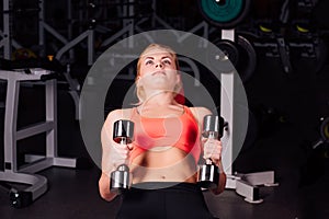 girl doing exercises in her pectoral muscle. fitness with dumbbells in the gym. nice cute female.