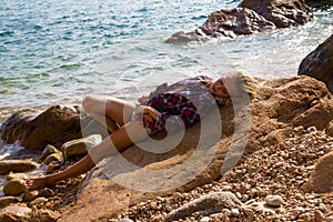 Girl in flannel shirt on the rocky beach