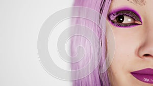 Sexy girl with glowing makeup and violet hair giving a seductive look in the studio on a white background - modern voque