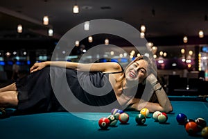 sexy girl lies on the snooker table among the balls