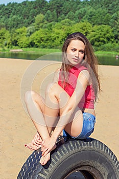 girl with long dark hair sitting in shorts on the beach on the wheel on a Sunny day