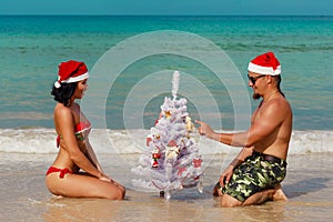 girl man Santa on a beach fir-tree