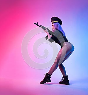 A sexy girl in a military or police uniform poses with a Kalashnikov assault rifle on a neon background