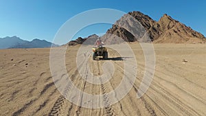 Sexy girl is riding a quad bike in the desert of Egypt. Dynamic view in motion.