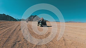 Sexy girl is riding a quad bike in the desert of egypt. Dynamic view in motion.