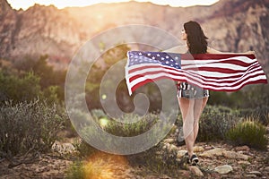 Sexy girl standing with american flag in nevada desert at sunset