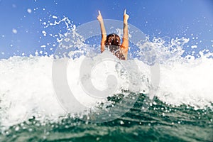 girl swim sea waves hands up splash back view