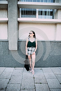 Sexy girl in a T-shirt, sunglasses and mini shorts near the wall photo