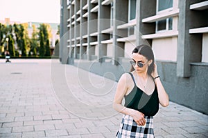 Sexy girl in a T-shirt, sunglasses and mini shorts near the wall photo