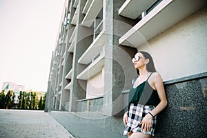 Sexy girl in a T-shirt, sunglasses and mini shorts near the wall photo