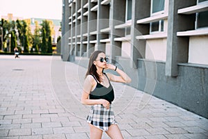 Sexy girl in a T-shirt, sunglasses and mini shorts near the wall photo