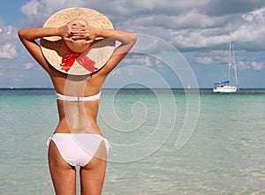 girl on tropical beach. Beautiful young woman with sun hat