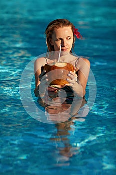 Sexy girl with tropical flower in hair and coconut in hands