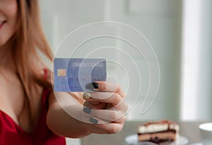 Sexy girl wearing a red dress. Hold a credit card in hand. Electronic cards are convenient easy to make financial transactions. No