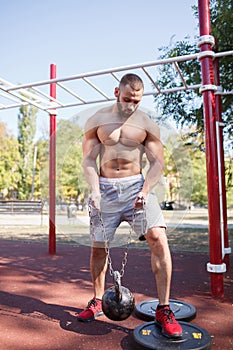 Sexy, hot muscular sportsman doing exercises in the park. A strong boy on a natural background. Sports concept.