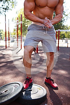 Sexy, hot muscular sportsman doing exercises in the park. A strong boy on a natural background. Sports concept.