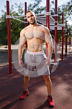 Sexy, hot muscular sportsman doing exercises in the park. A strong boy on a natural background. Sports concept.