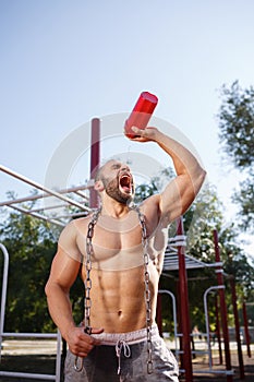 Sexy, hot muscular sportsman doing exercises in the park. A strong boy on a natural background. Sports concept.