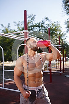 Sexy, hot muscular sportsman doing exercises in the park. A strong boy on a natural background. Sports concept.