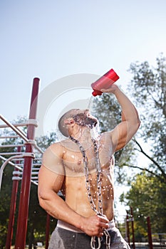 Sexy, hot muscular sportsman doing exercises in the park. A strong boy on a natural background. Sports concept.