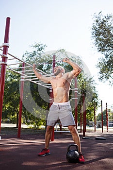 Sexy, hot muscular sportsman doing exercises in the park. A strong boy on a natural background. Sports concept.