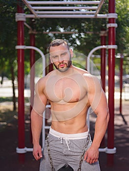 Sexy, hot muscular sportsman doing exercises in the park. A strong boy on a natural background. Sports concept.