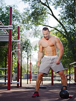 Sexy, hot muscular sportsman doing exercises in the park. A strong boy on a natural background. Sports concept.