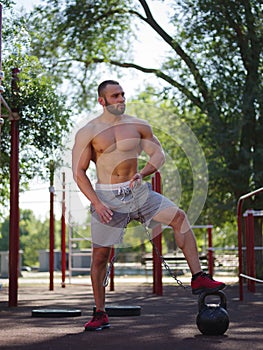 Sexy, hot muscular sportsman doing exercises in the park. A strong boy on a natural background. Sports concept.