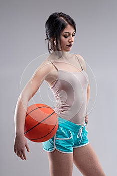 Sexy jaunty young woman posing with a basketball