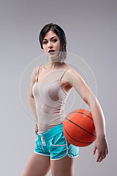 Sexy jaunty young woman posing with a basketball photo