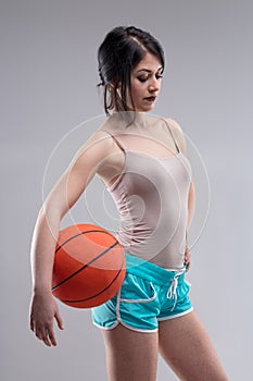 Sexy jaunty young woman posing with a basketball photo