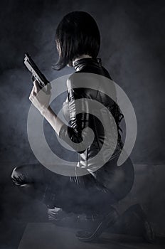 Sexy killer female assassin with a gun wearing black leather