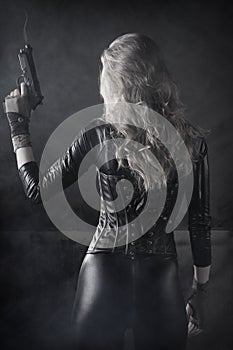 Sexy killer female mercenary with a gun wearing black leather