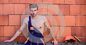 Sexy laborer. Attractive worker. Handsome man wear overalls. Construction. Worker brick wall background. Perform basic