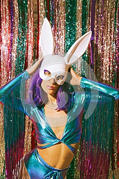 Sexy Lady 80s  fashion in stylish holographic party look and rabbit mask. Tinsel installation. New year`s clubbing concept. Merry