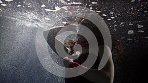 Sexy lady with red whip is swimming underwater in bubbles and light, mysterious and magic shot