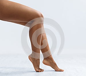 Sexy legs of black woman over grey background, cropped