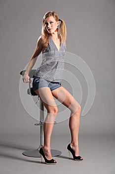 long legged blonde model sitting on bar stool