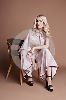 luxurious woman in a dress sitting on a chair. Autumn collection of women clothing. Fashion blonde in a long beautiful dress