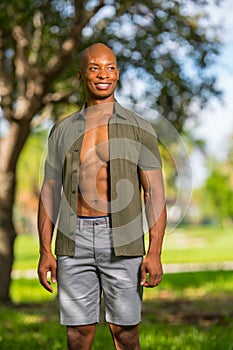 Sexy male model posing in the park with shirt unbuttoned showing muscle chest