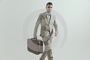 Sexy man in his 40s wearing suit, holding luggage and travelling