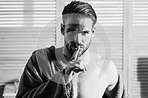 Sexy man show silence finger gesture. Guy with muscular torso in underwear, bathrobe on bath.