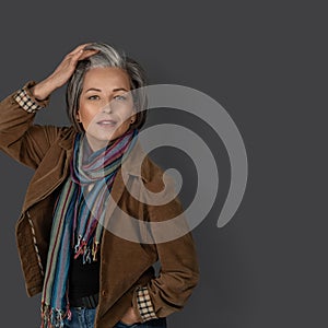 Sexy mid aged woman touches her graying hair and looks at the camera. Studio portrait of fashion lady in casual