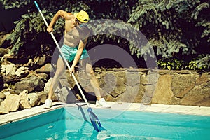 Sexy muscular man cleaning swimming pool